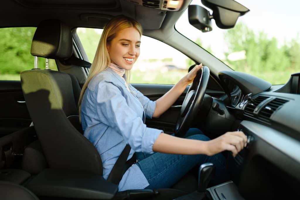 Smiling female student in the car, driving school